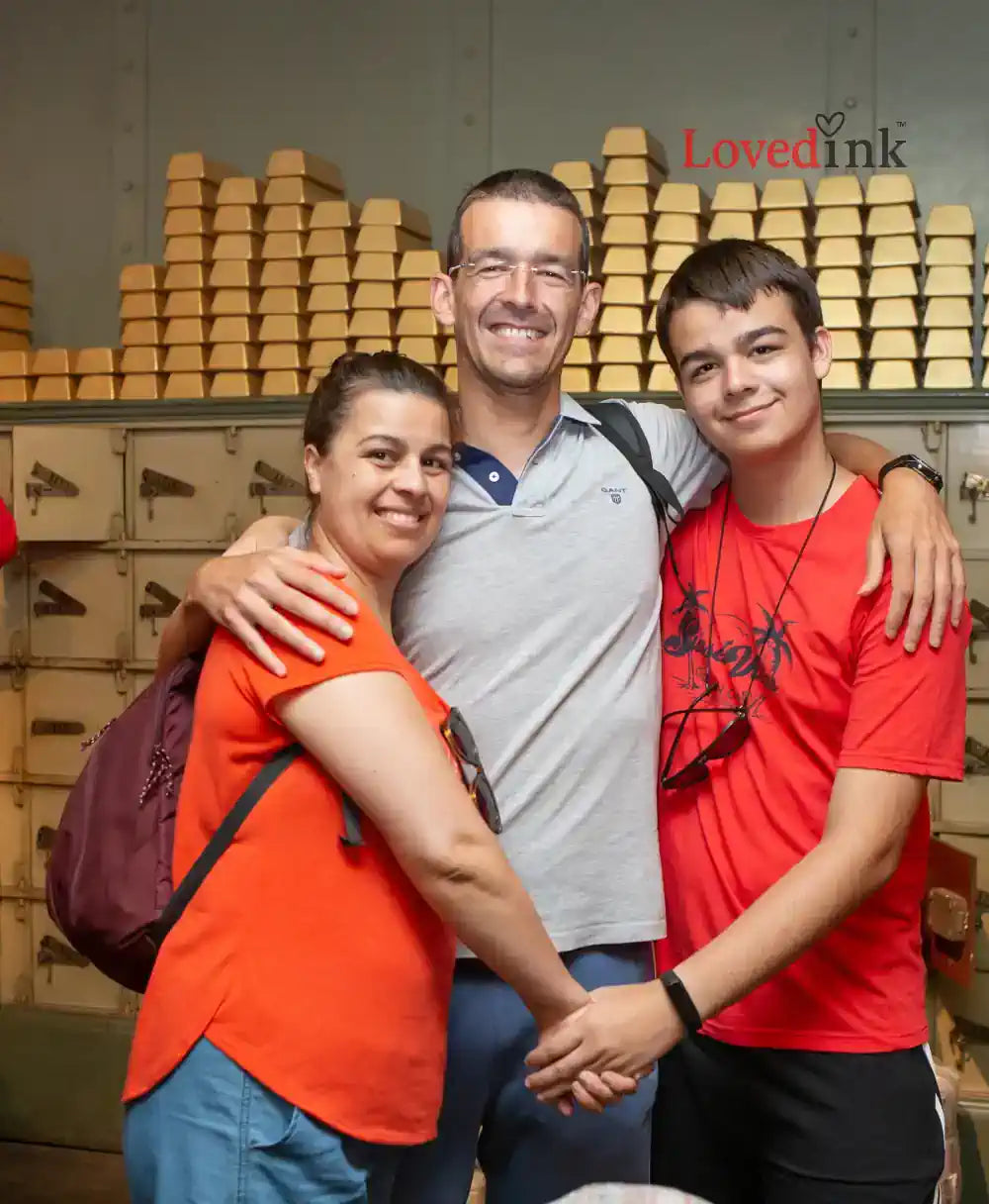 Three people posing together with stacked boxes in the background, featuring the 'LovedInk' brand.