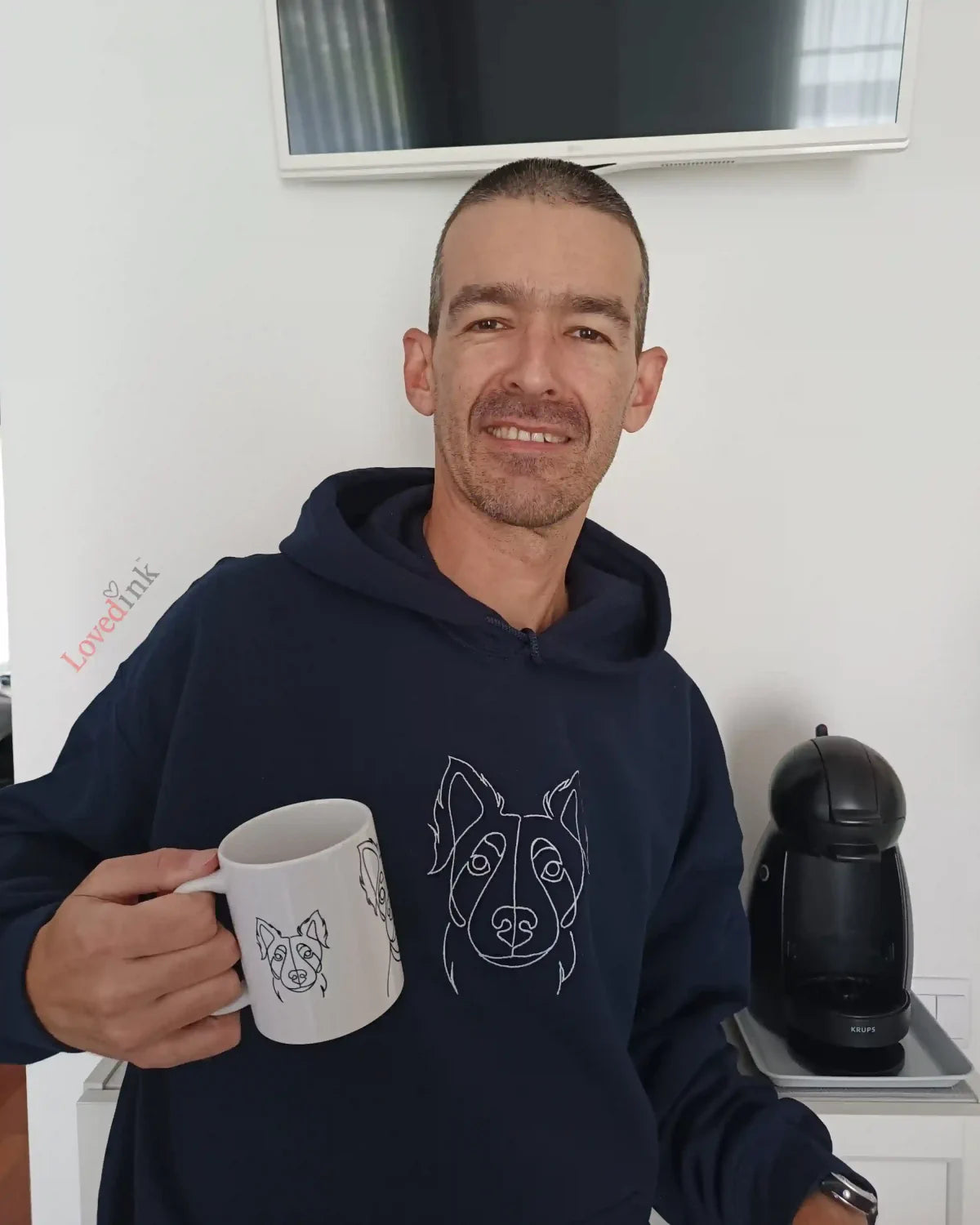 Man wearing navy custom embroidered hoodie with minimalist pet line art holding a mug (Lovedink)