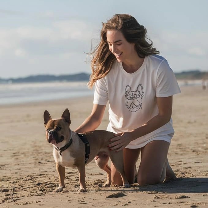 Woman at beach with French Bulldog wearing white custom t-shirt with minimalist pet line art (Lovedink)
