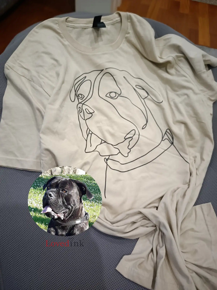 lat lay of beige custom t-shirt with minimalist dog line art — personalized pet gift (Lovedink)